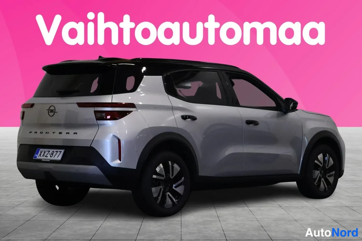 Takaviisto: Silver Opel Frontera SUV rear three-quarter view showing black roof rails, LED taillights, 'FRONTERRA' badging and license plate against pink studio background
