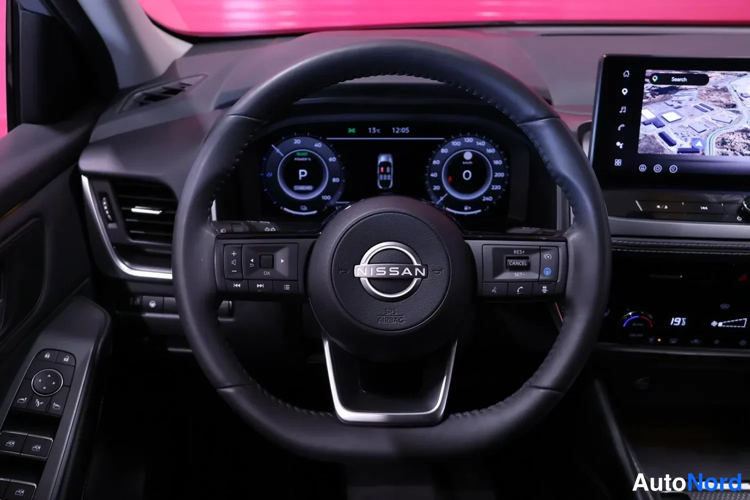 Muu: Ohjauspyörän takaa otettu kuva: Nissan-merkitty ohjauspyörä, digitaalinen mittaristo, jossa vaihde P ja nopeus 0, sekä kosketusnäyttö.