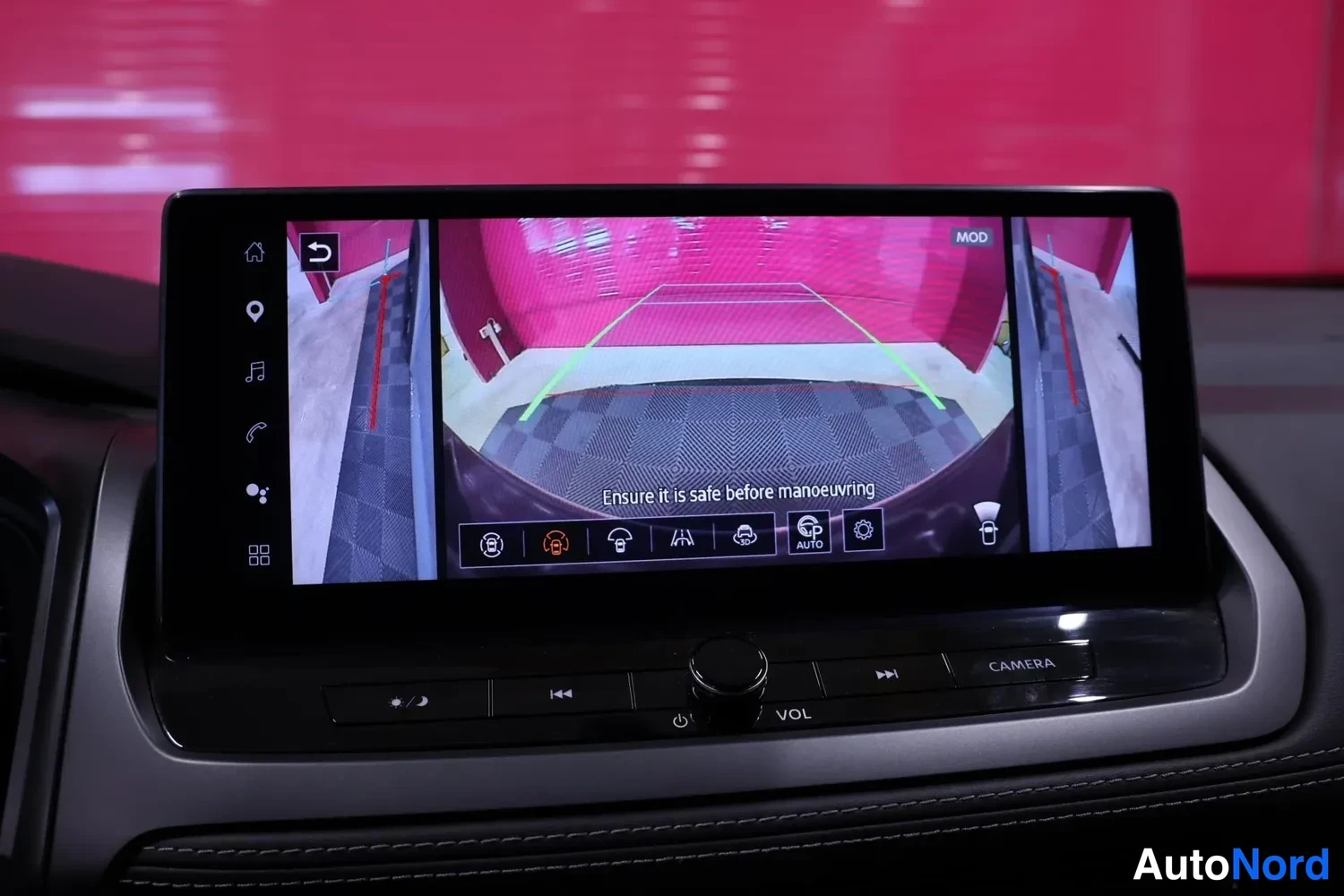 Yksityiskohta: Infotainment-näyttö takakameran kuvalla ja sivukameroiden näkymillä, ohjeteksti 'Ensure it is safe before manoeuvring' näkyvissä.