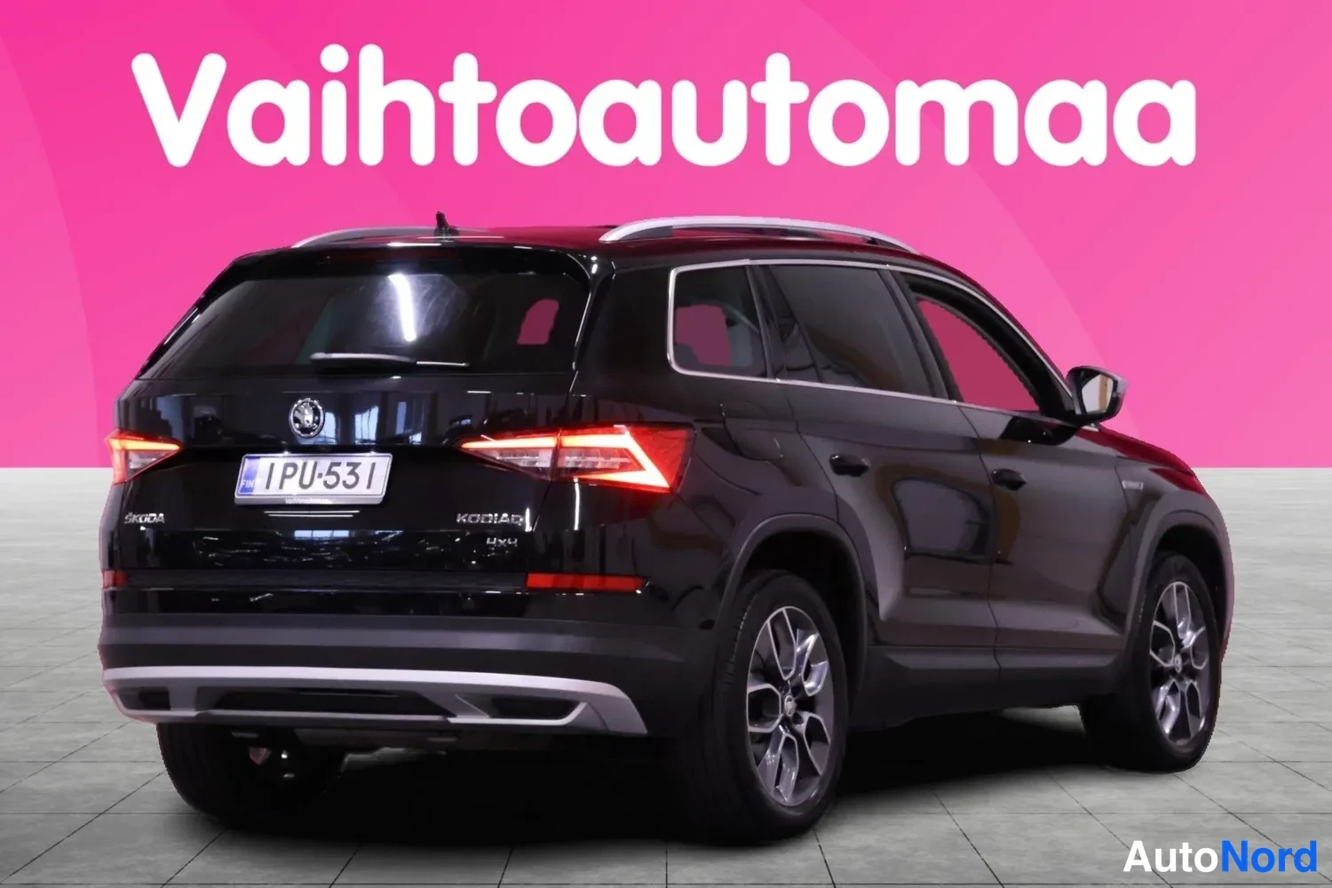 Takaviisto: Musta Skoda Kodiaq kolmesta neljänneksestä takaa vasemmalla, takavalo sytytettynä, rekisteritunnus.