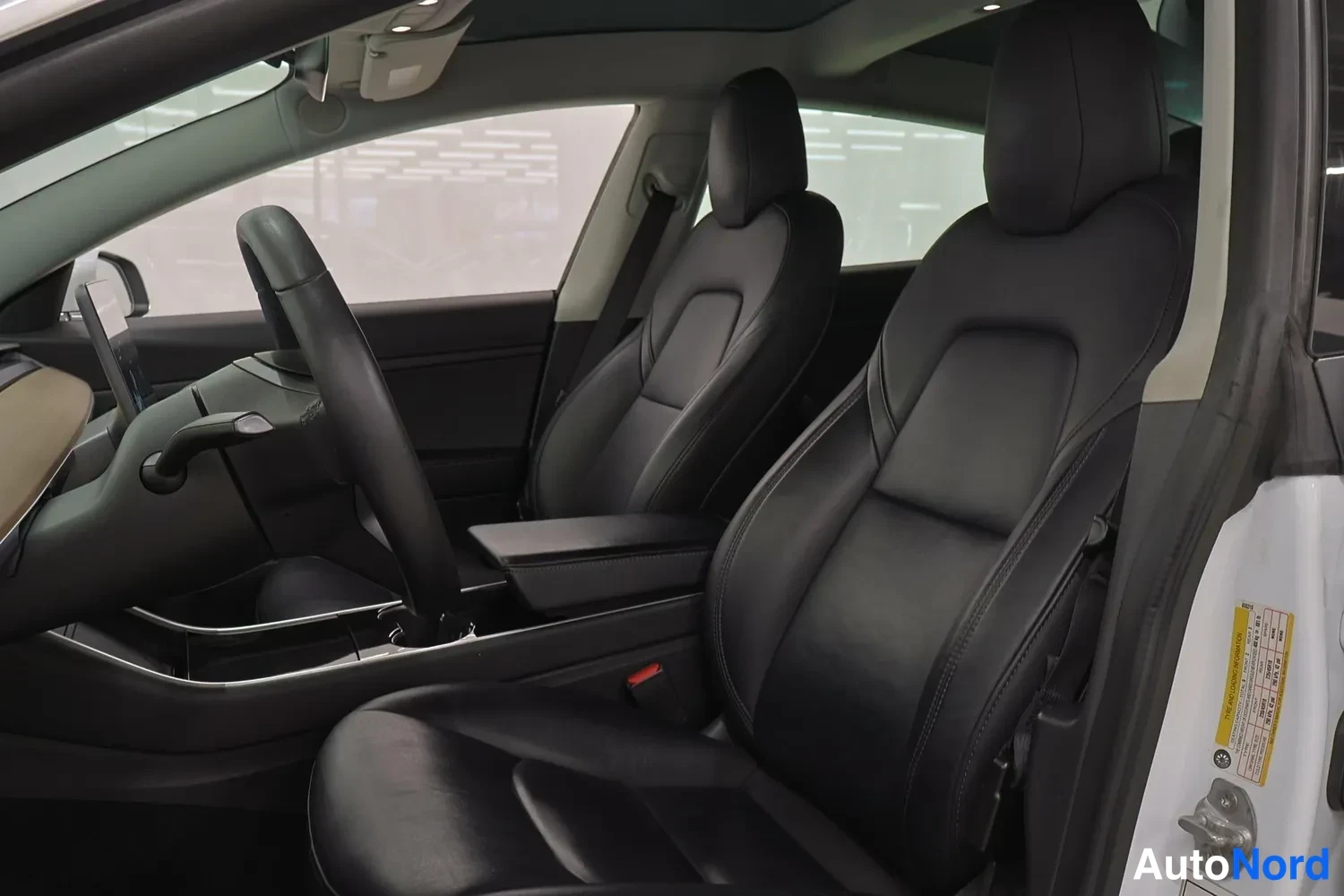 Muu: Tesla Model 3:n etusohva ja ohjaamo mustat nahkaistuimet, puupaneloiden keskikonsoli ja juuriajettu selkänoja.