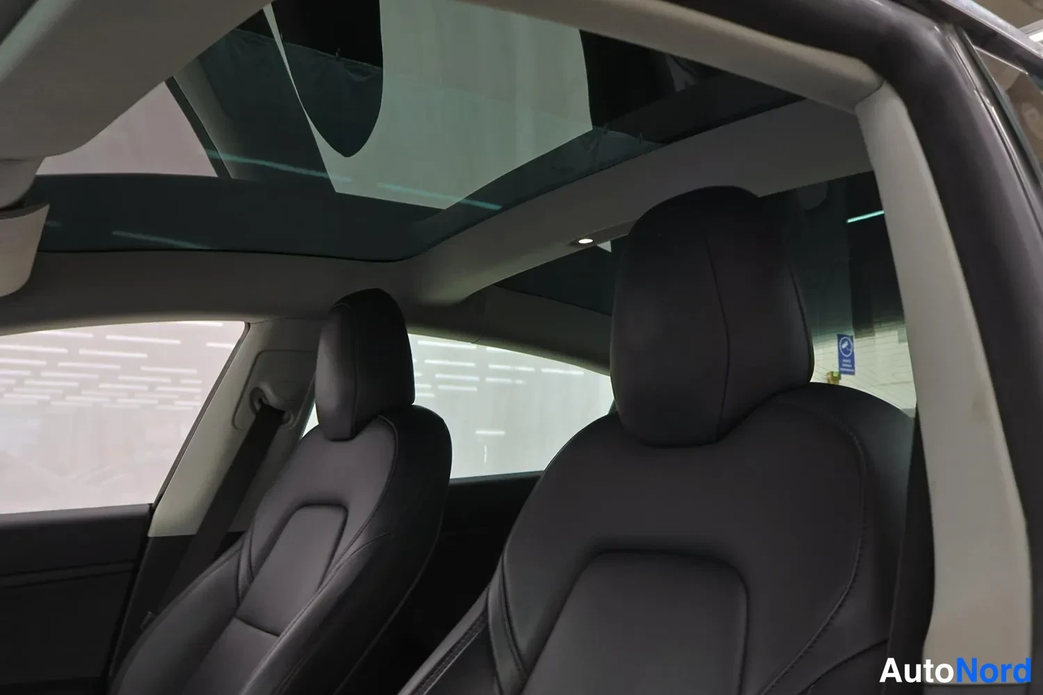 Muu: Tesla Model 3:n sisätilat laaja lasikatto ja mustat nahkaistuimet.