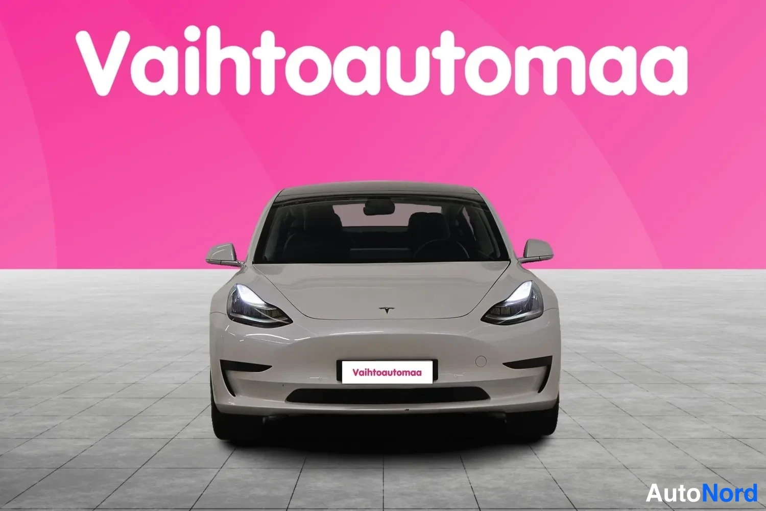 Edestä: Tesla Model 3 -henkilöauto suoraan edestä päin kuvattuna, valkoisella korilla ja LED-etuvaloilla.