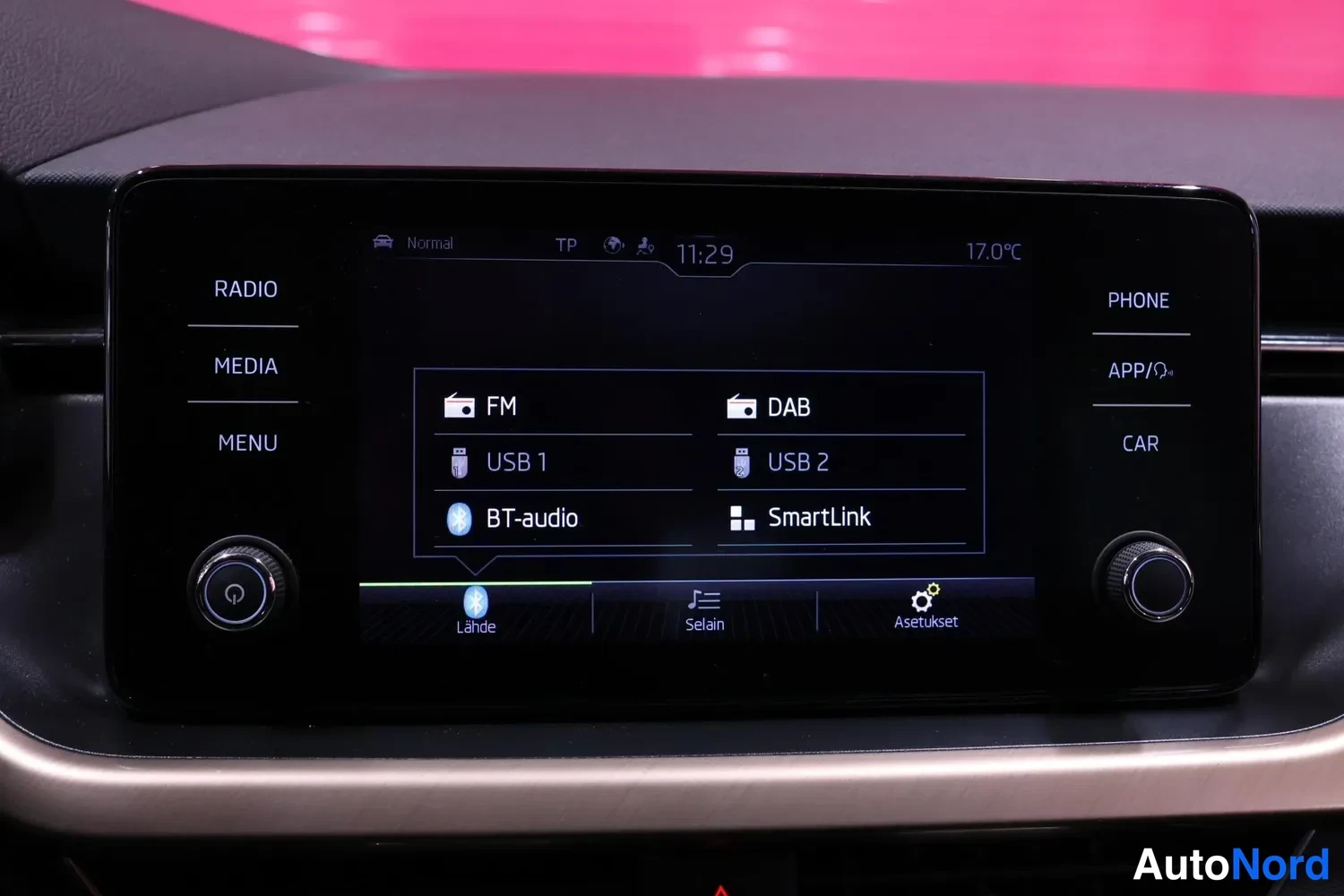Yksityiskohta: Keskiotsakkeen infotainment-näyttö lähikuvassa, kuvaruudulla lähdeluettelo (FM, DAB, USB 1, USB 2, BT-audio, SmartLink), kellonaika 11:29 ja lämpötila 17,0 °C,