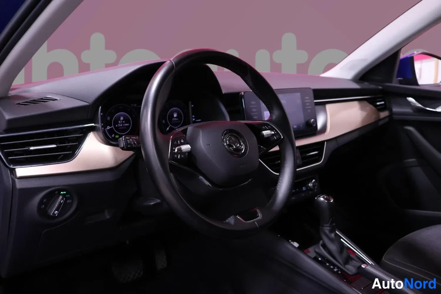 Muu: Autojen sisätila: ohjauspyörä Skoda merkeillä, digitaalinen mittaristo ja kosketusnäyttö keskiösselässä, tumma sisusta.