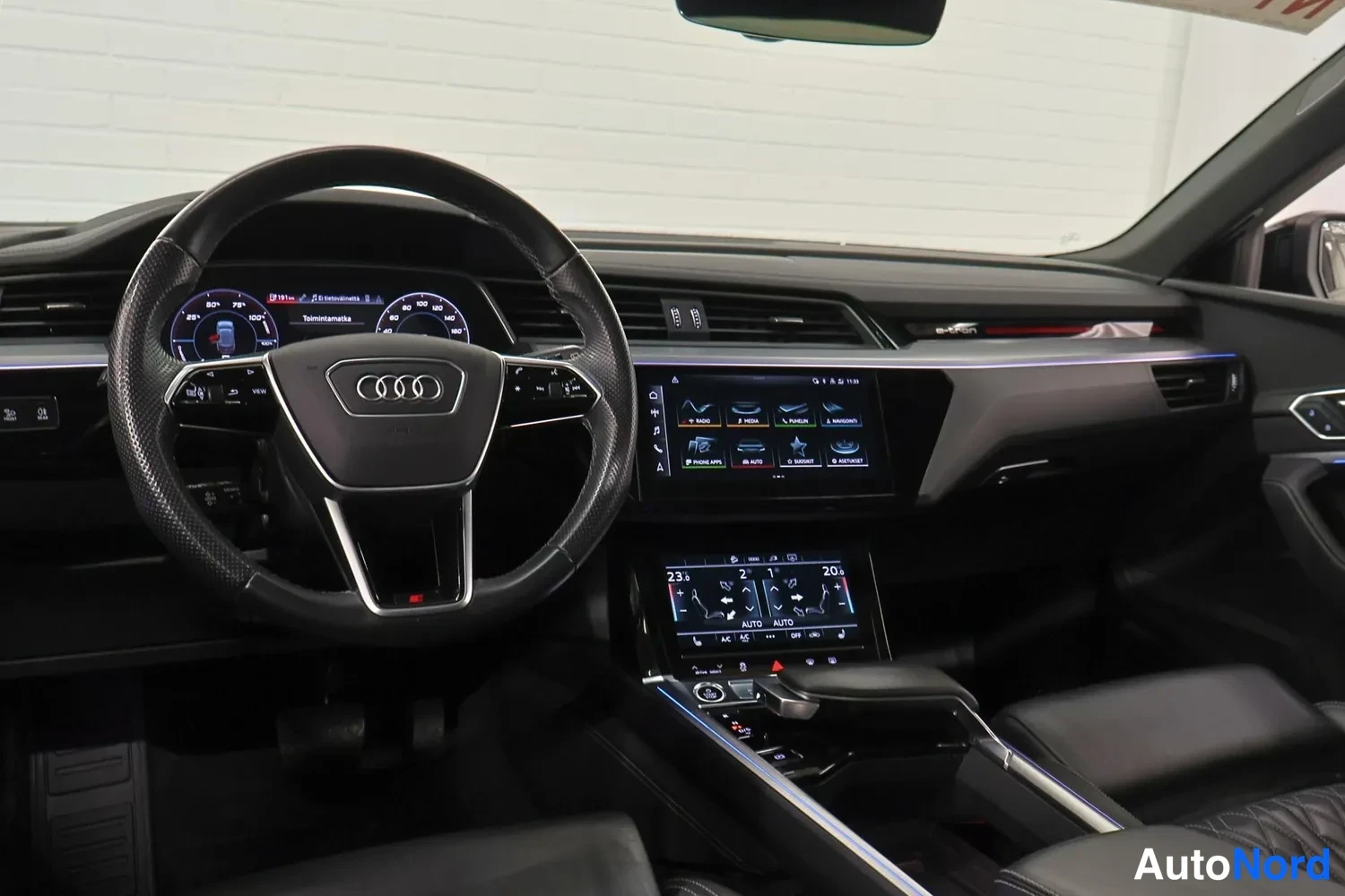 Muu: Sisäkuva koko kojelaudasta: Audi-ohjauspyörä, digitaalinen mittaristo, kaksi kosketusnäyttöä keskikonsolissa ja mustat urheiluistuimet.