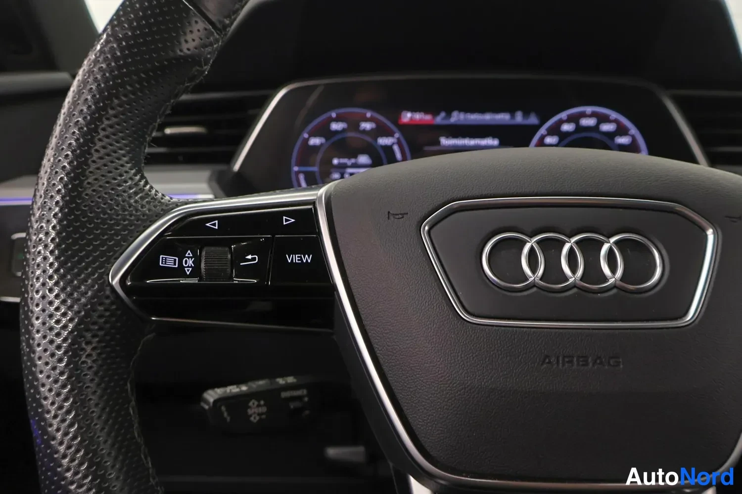 Yksityiskohta: Audi-merkillä varustettu ohjauspyörä ja osa digitaalisesta mittaristosta.