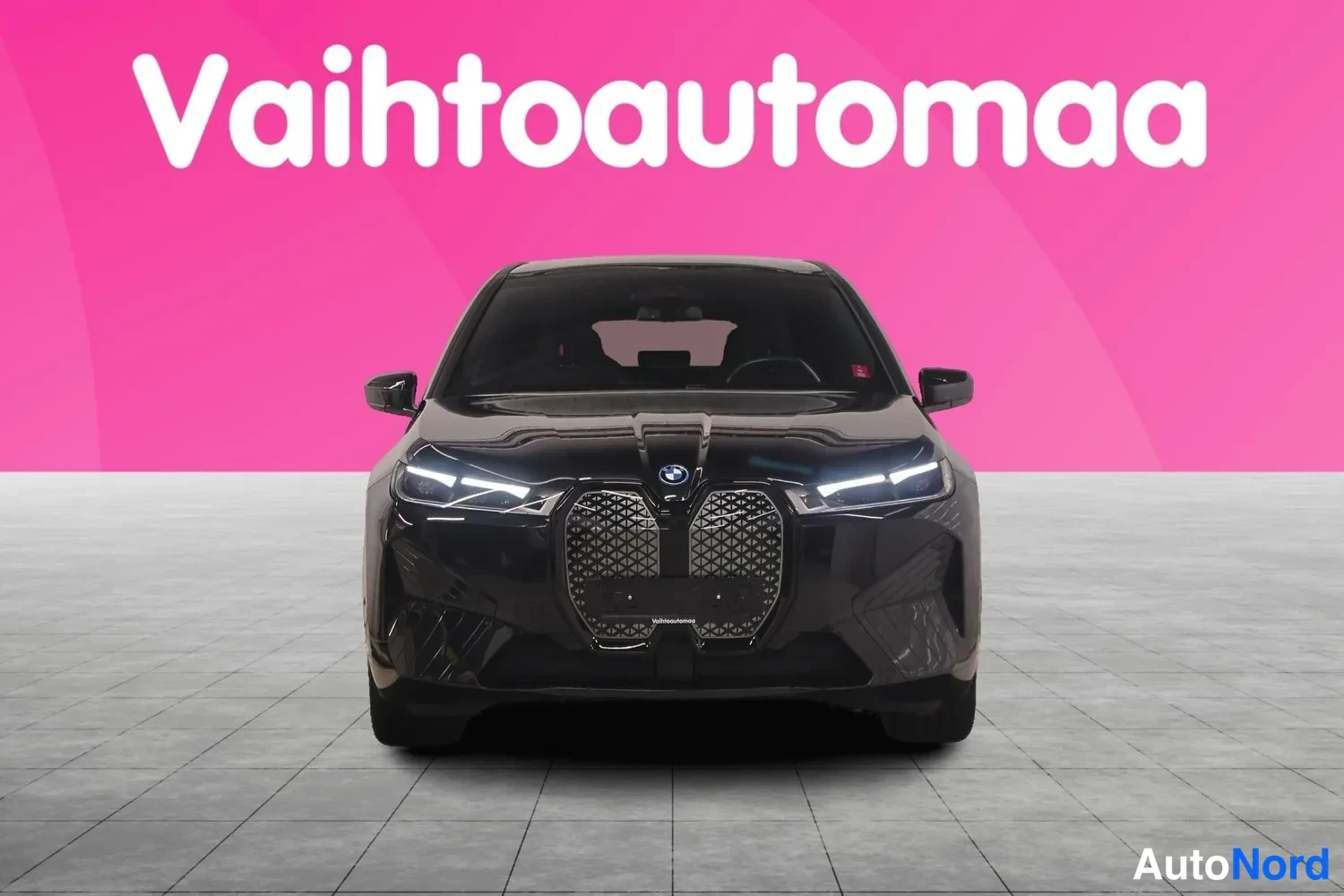 Edestä: Mustan BMW:n suora etunäkymä, etusäleikkö ja ajovalot näkyvät.