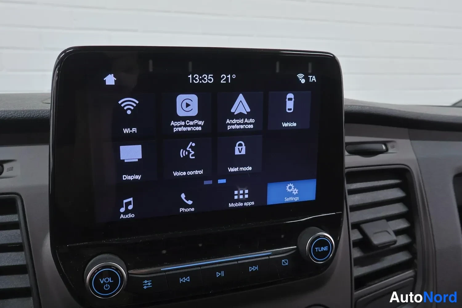 Yksityiskohta: Infotainment-näytön asetussivu vaihtoehdoilla Wi-Fi, Apple CarPlay preferences, Android Auto preferences, Vehicle, Display, Voice control ja Valet mode, kello 1