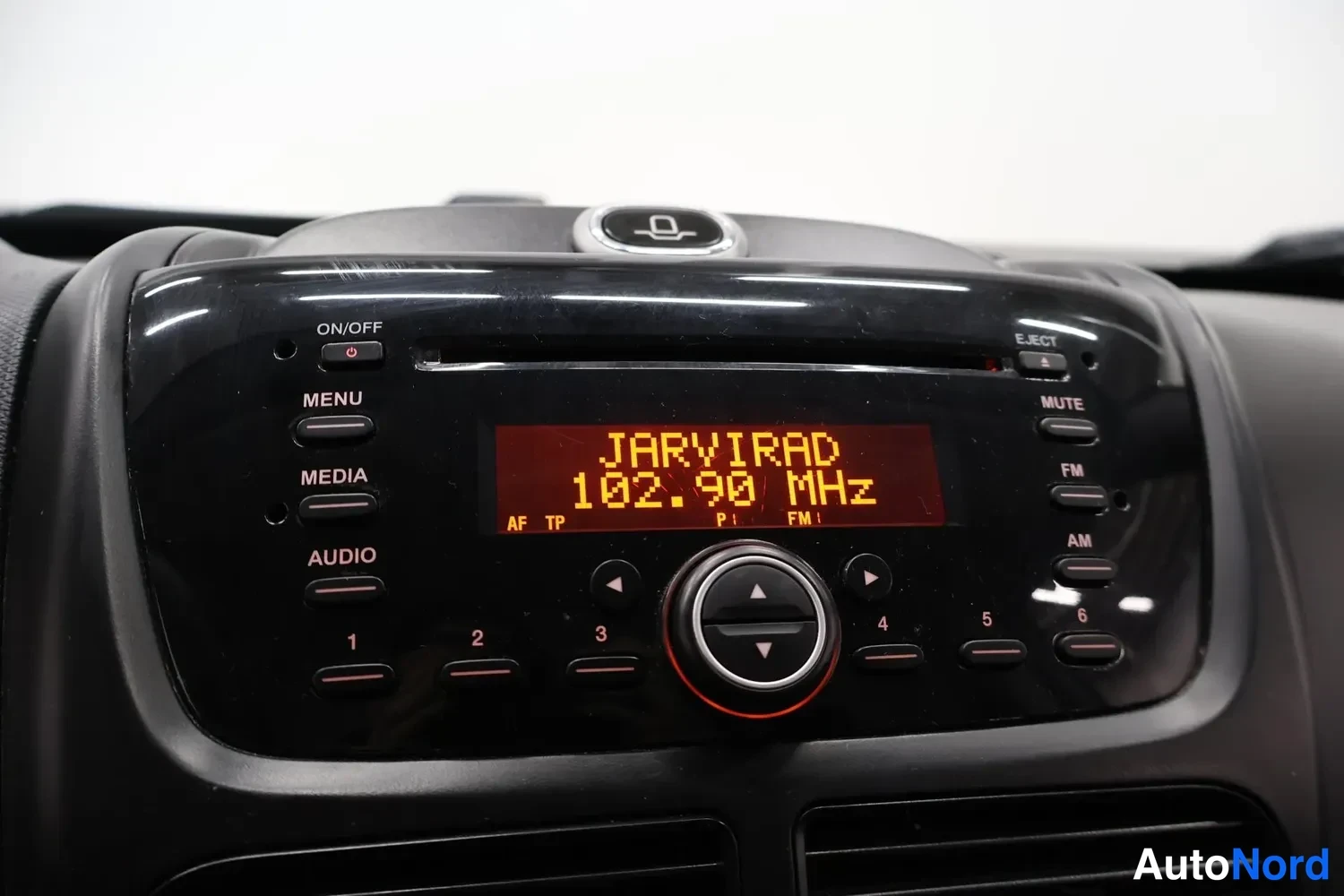 Yksityiskohta: Autoon sisäänrakennettu radio-CD-soitin, näytöllä teksti JARVIRAD 102.90 MHz.