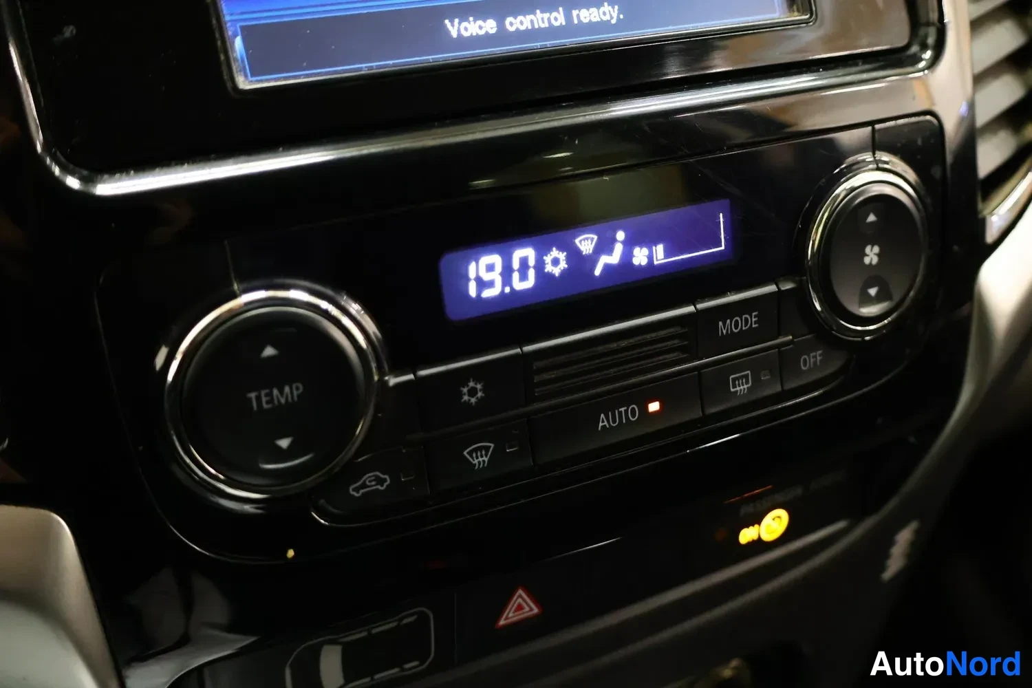 Muu: Autoradion ja automaattisen ilmastoinnin säätimet sisätiloissa; näytössä teksti 'Voice control ready.' ja lämpötila 19.0, painikkeet TEMP, AUTO, MODE ja OFF.