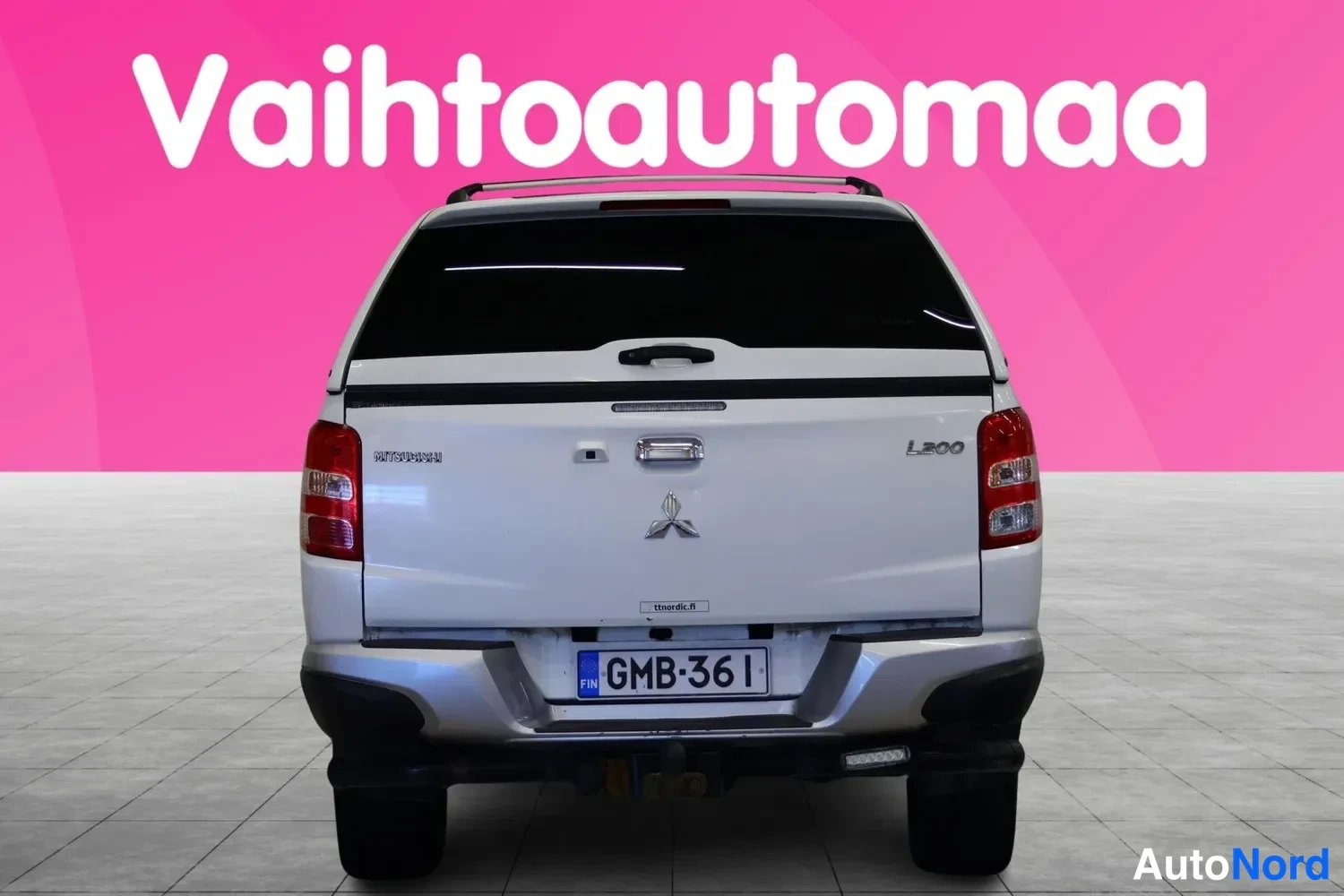 Takaa: Mitsubishi L200 suoraan takaa valkoisena, kannessa L200-merkintä ja rekisteritunnus.