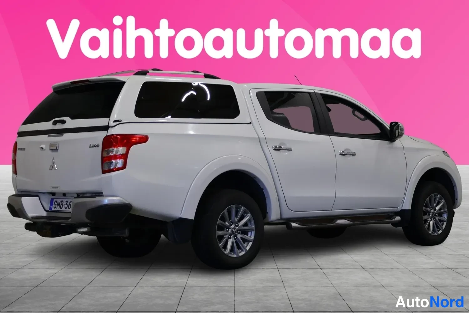 Takaviisto: Auton takaosan kolmasosa vasemmalta: valkoinen lava-auto, jossa musta lavakate, takaiskut, kylkipalkit ja rekisteri.