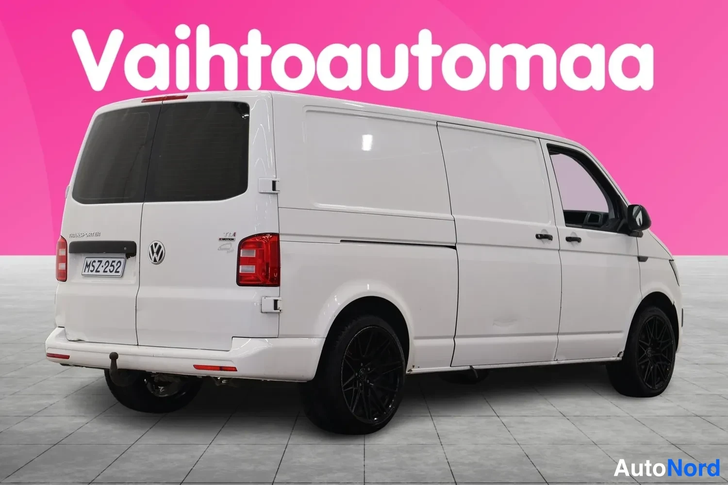 Takaviisto: Valkoinen pakettiauto takaa-vinosti vasemmalta, rekisteritunnus, mustat vanteet.