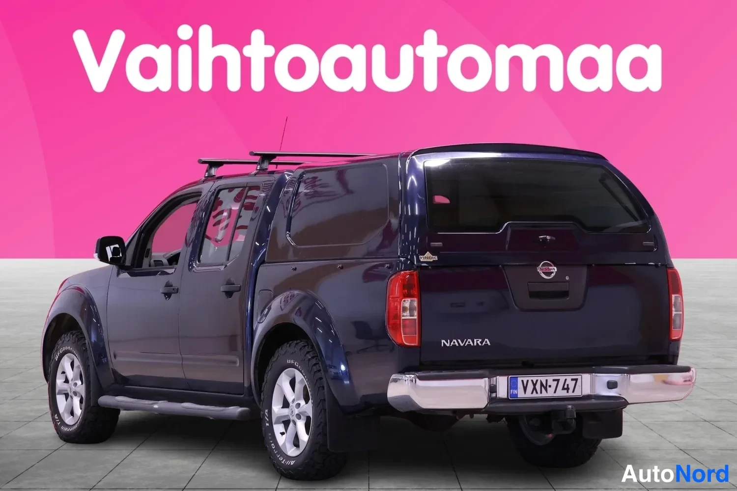 Takaviisto: Nissan Navara -farmarimallisella kupeella takaa viistosti oikealta; tummansininen koripelti, NAVARA-teksti ja -rekisteri.