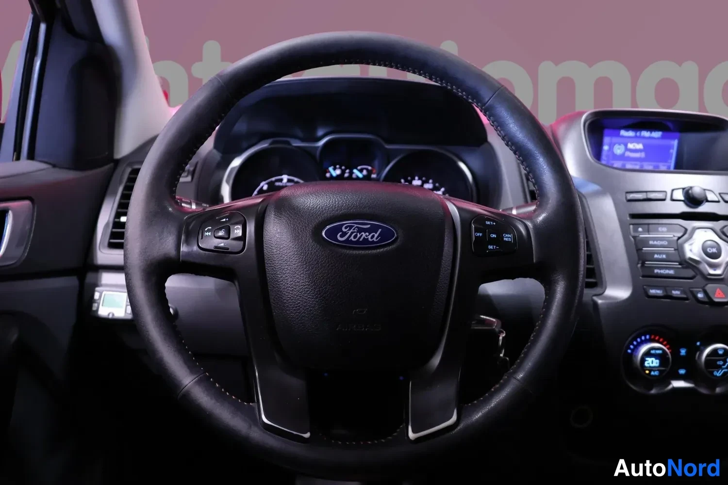 Yksityiskohta: Ford-merkkinen ohjauspyörä, cooparit ja osa kojelaudasta: radio-näyttö ja puhekytkimet.
