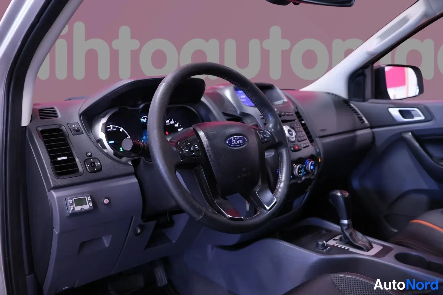 Muu: Ohjaamo vasemmalta katsottuna: Ford-merkillä varustettu ohjauspyörä, mittarit, keskikonsolin automaattivaihteen valitsin ja infotainment-näyttö.