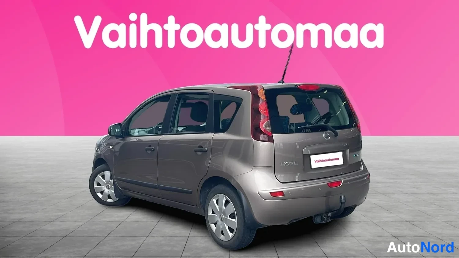 Takaviisto: Nissan Note, takakulmakuva vasemmalta, ruskeanharmaa; takavaloissa ja peräluukussa lisäteksti heijastuu