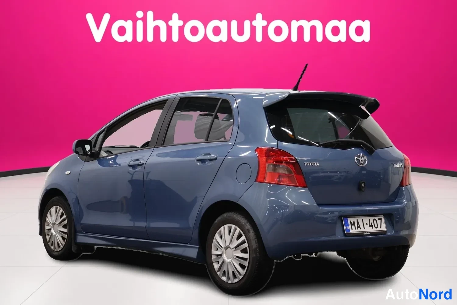 Takaviisto: Sininen Toyota Yaris -viistoperä takaa oikealta vasemmalle kuvattuna, rekisteritunnus