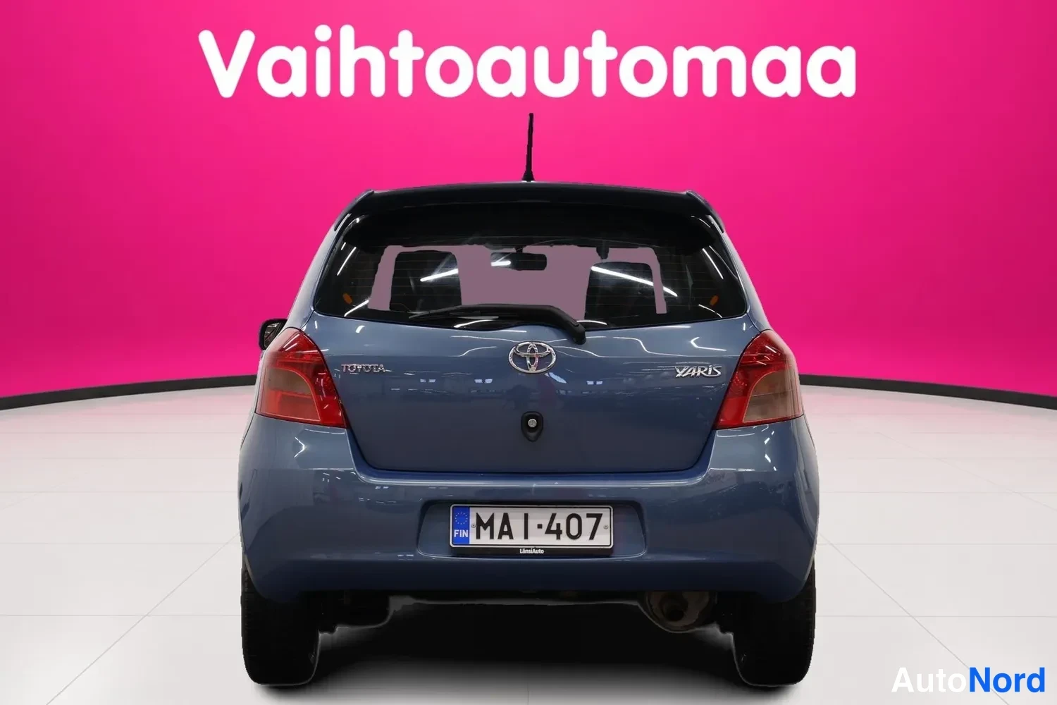 Takaa: Sininen Toyota Yaris -viistoperä suoraan takaa kuvattuna, rekisteritunnus