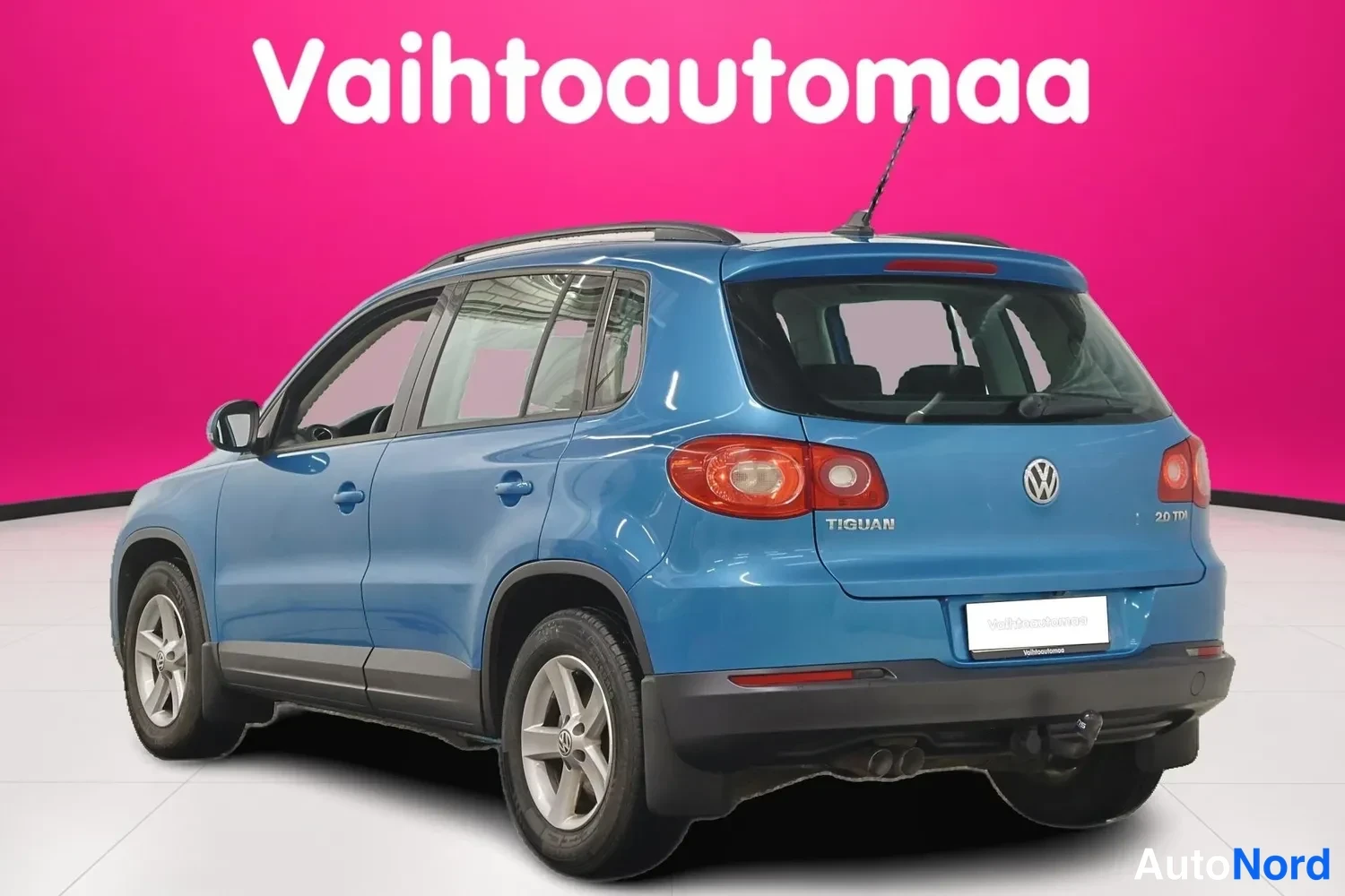 Takaviisto: Sininen Volkswagen Tiguan takaviistöstä, perä ja vasen kylki näkyvät, takaovissa TIGUAN-teksti.