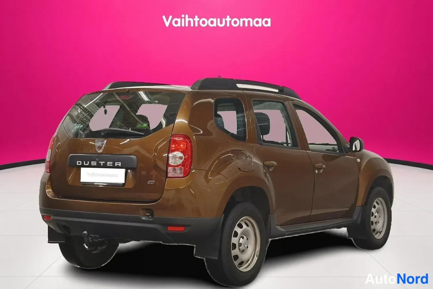 Takaviisto: Ruskea Dacia Duster takaa kulmasta kuvattuna; takapuskuriin kiinnitetty vetokoukku ja takana DUSTER-teksti näkyvissä.