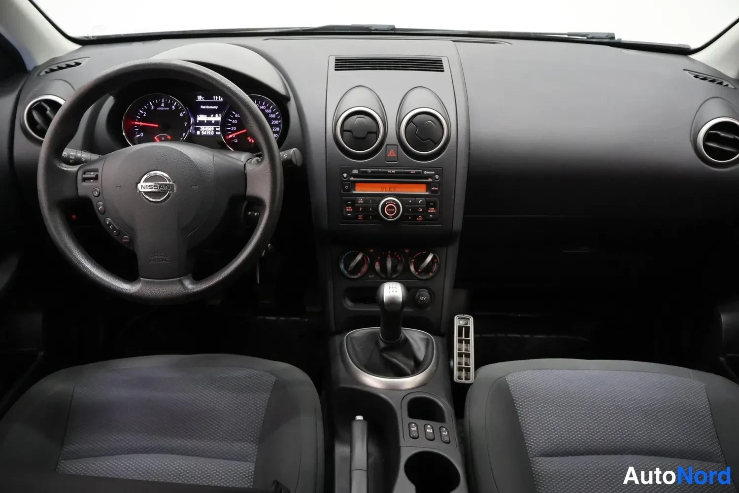 Muu: Ohjaamo ylhäältä kuvattuna: Nissan-ohjauspyörä, manuaalivaihteisto, kaksiosainen keskinäköinen matkustaja ja kaksi etuistuinta.