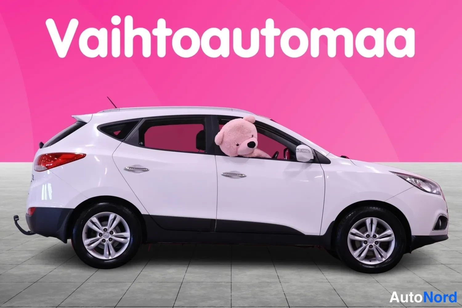 Sivulta: Valkoinen Hyundai ix35 sivukuva oikealta puolelta, nallekeini takapyörän vieressä, vaaleat vanteet.