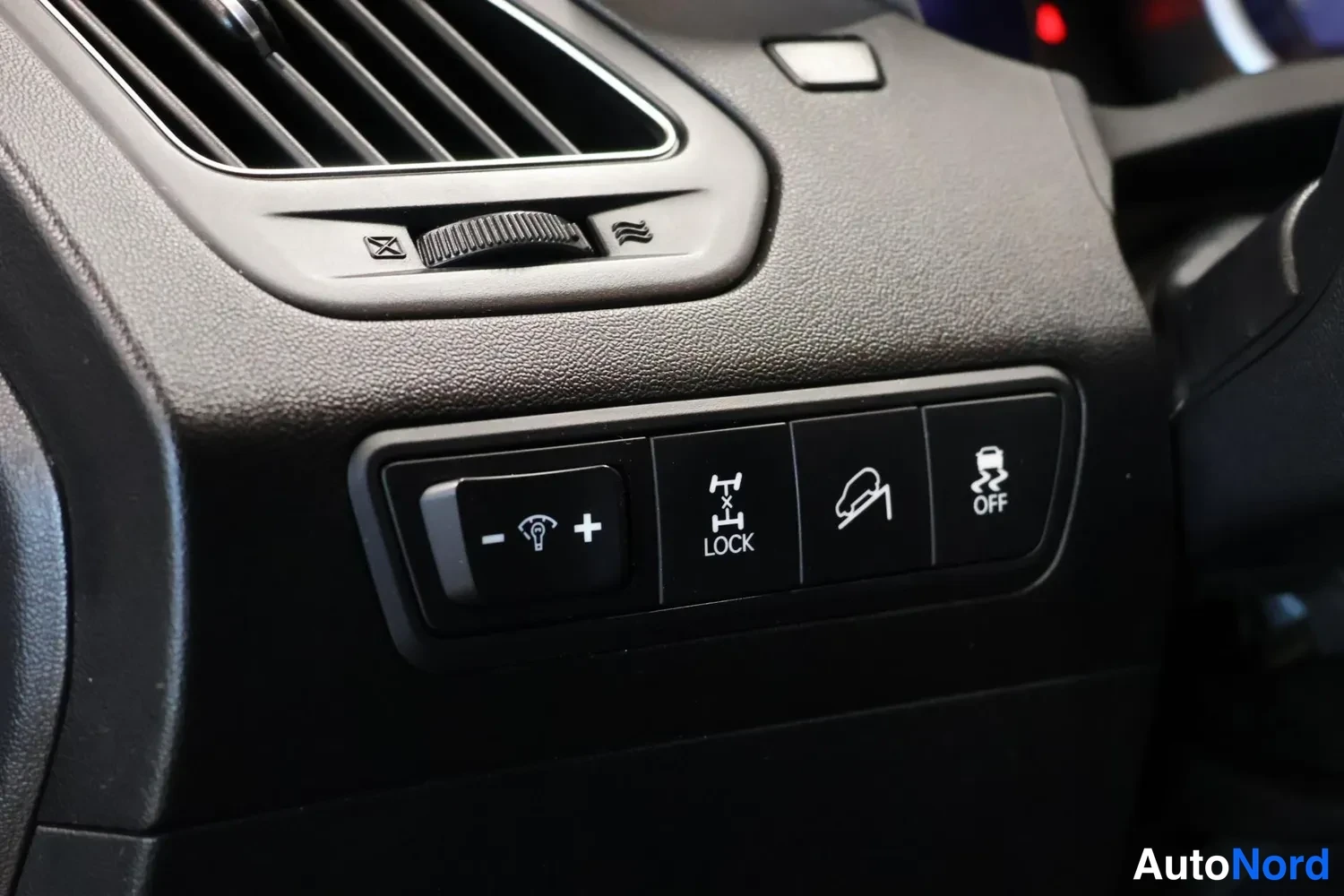 Ohjaamo: Auton sisäosa, ohjaamon keskiosa. Katsojan edessä on panelleja: painikkeita LED-valojen säädöille (+/-), 'LOCK'-painike (mahdollisesti diff-lock), alamäkijarrun