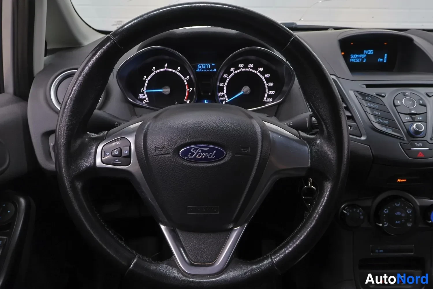 Muu: Lähikuva Ford-ohjauspyörästä ja mittaristosta, matkamittari 63971 km, vaihteistossa vapaasignaali.