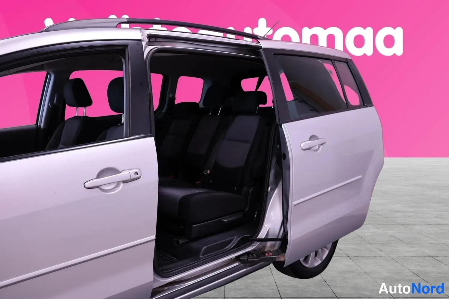 Takaviisto: Hopeanharmaa Mazda 5 -tilastaajasto sivulta takaa päin, takimmainen liukuova auki ja takaistuimet näkyvissä.