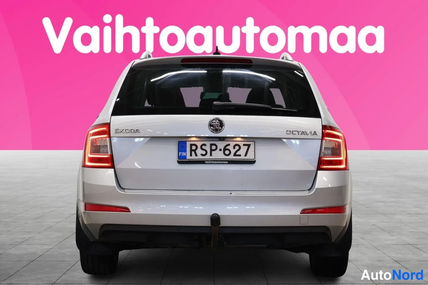 Takaa: Hopeanharmaan farmariauton takaosa suoraan takaa, ŠKODA- ja OCTAVIA-tekstit, rekisterikilpi ja vetoaisa näkyvät.