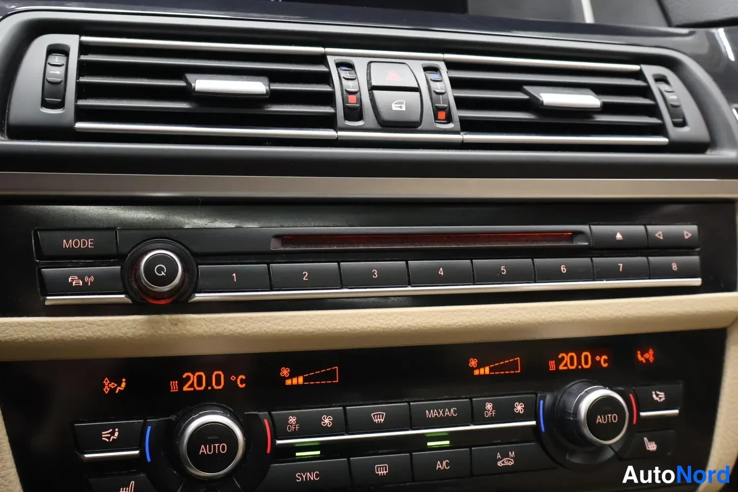 Muu: Keskiöraudan säätimet: ilmastointi näyttää 20,0 °C molemmilta puolilta, napit AUTO, SYNC, MAX A/C ja A/C, ylhäällä radio- ja ilmastointiteksti.