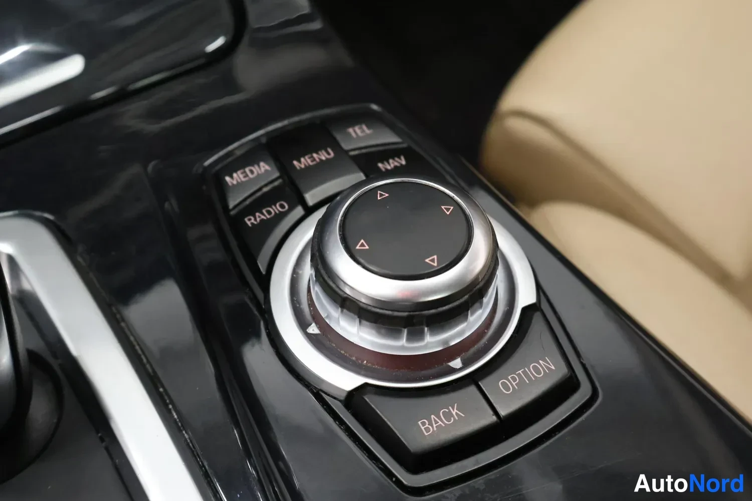 Yksityiskohta: BMW:n keskikonsolin iDrive-ohjainpyörä ja painikkeet MEDIA, MENU, TEL, NAV, RADIO, BACK ja OPTION.