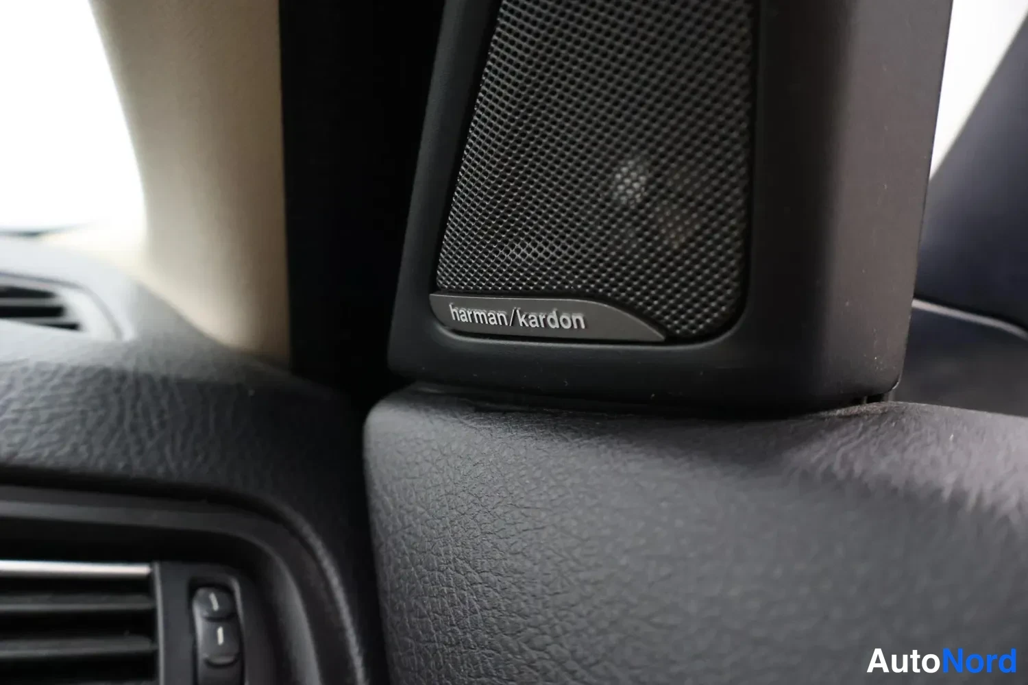 Yksityiskohta: harman/kardon-merkitty korvasarjan kaiutin A-pilarin tuntumassa.