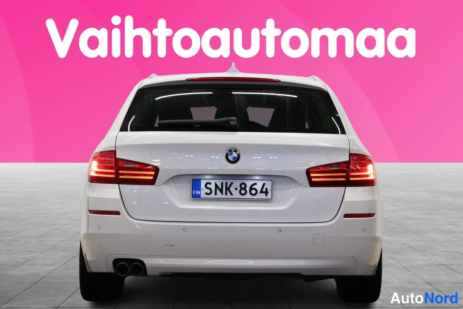 Takaa: BMW 5-sarjan farmariautu suoraan takaa, valkoinen, rekisteritunnus, kaksoispakoputki näkyy vasemmalla.