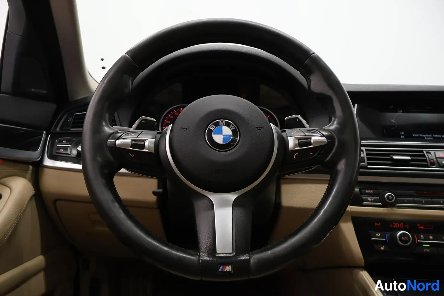 Edestä: Ohjauspyörä BMW-emblemalla ja M-merkinnällä, mittaristo ja osa kojelautaa näkyvät taustalla.