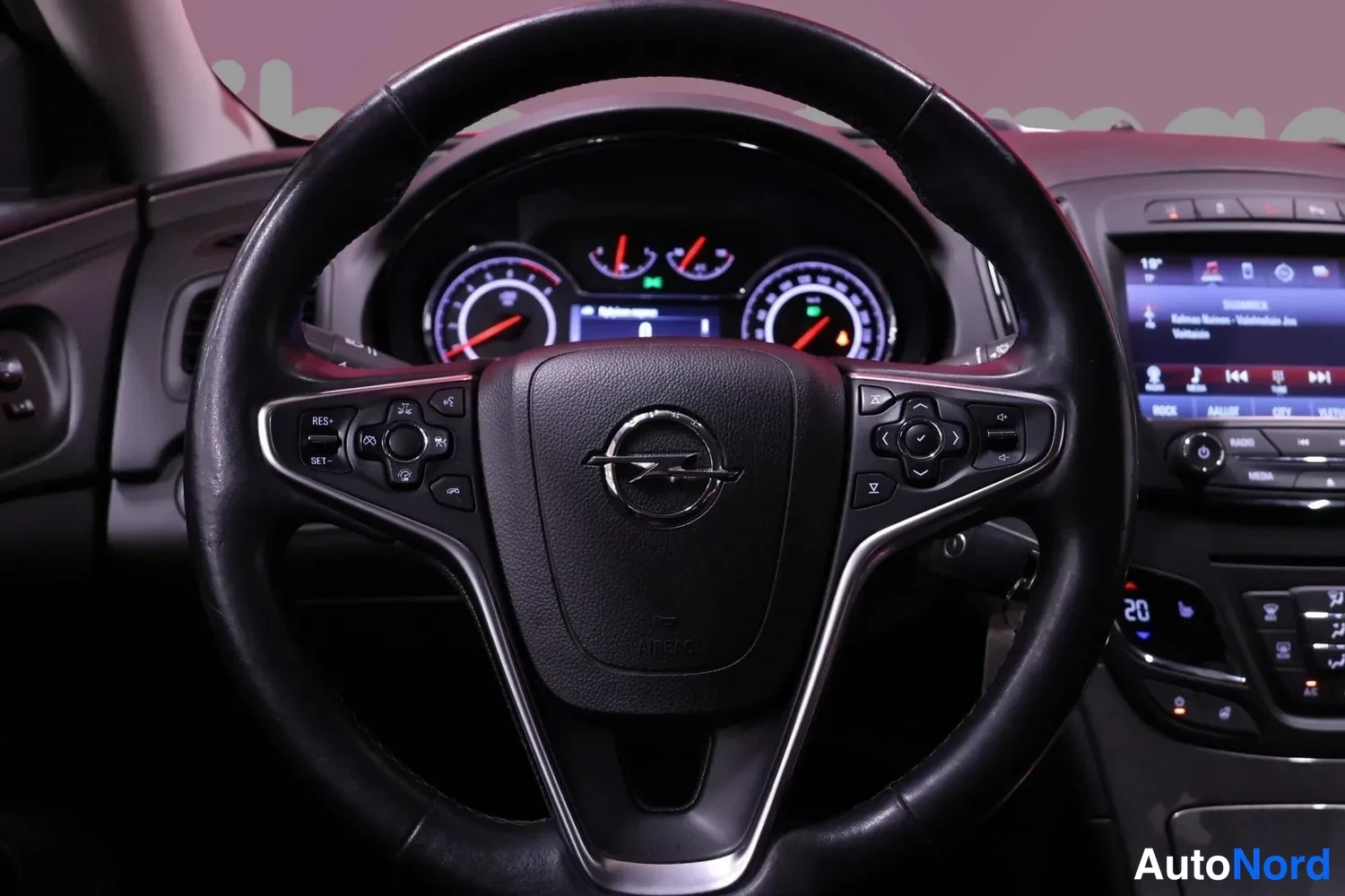 Edestä: Lähikuva Opel-merkillisestä ohjauspyörästä ja mittaristosta, osa keskikäyttölaitteesta näkyy oikealla.