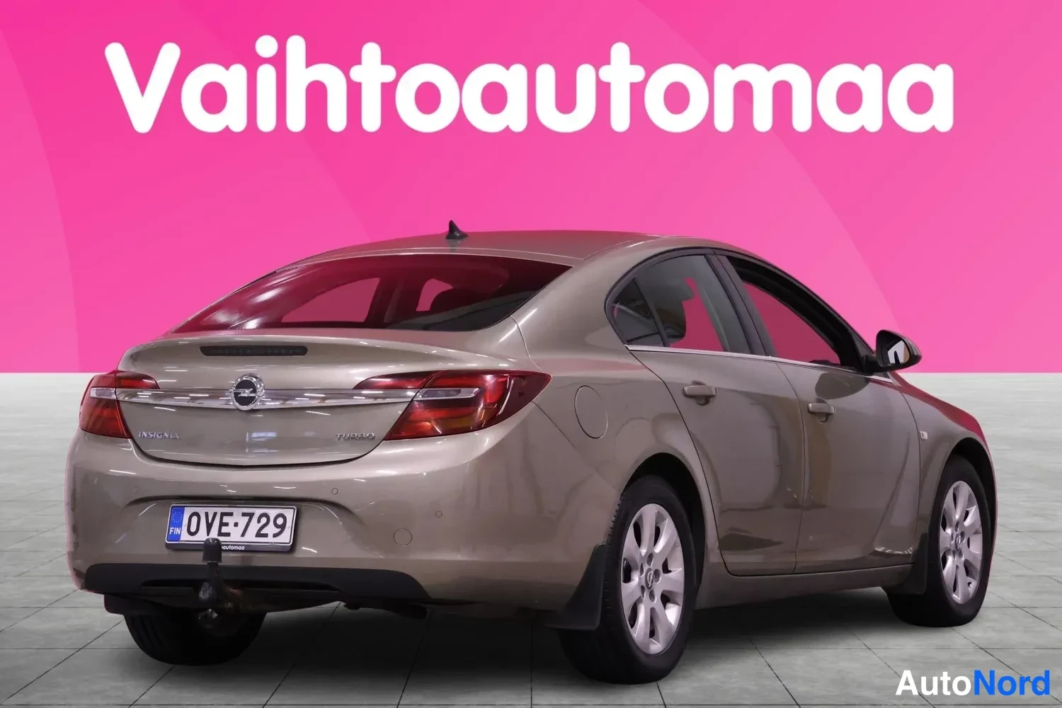Takaviisto: Ruskeanharmaan sedan-auton takakulma vasemmalta, rekisteritunnus.