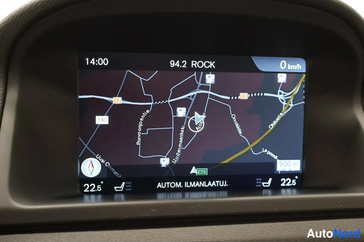 Muu: Paikann navigaattorin karttanäkymä keskikäyttöpaneelin näytössä, nopeus 0 km/h, kellonaika 14:00 ja kanava 94.2 ROCK.