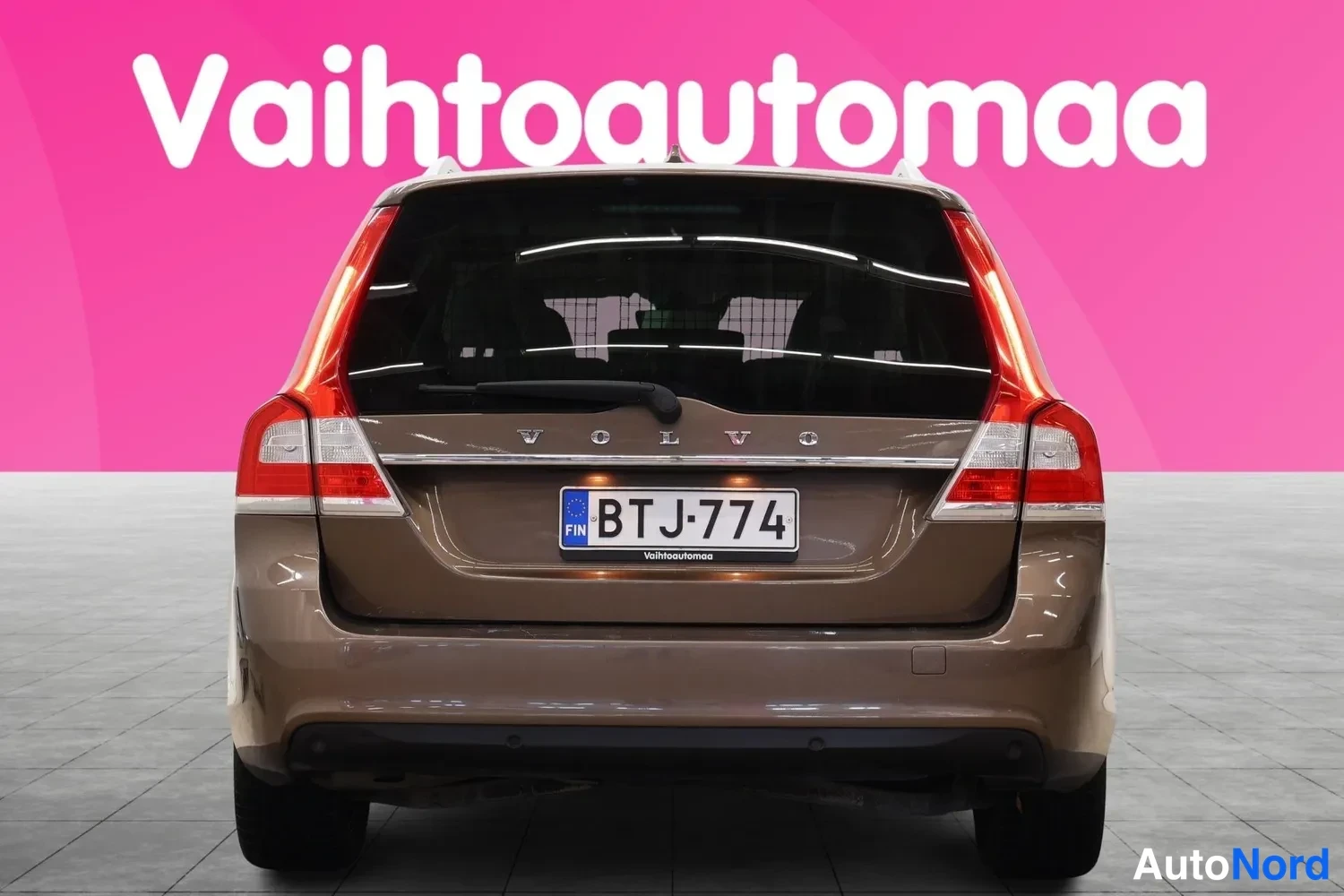Takaa: Car in gray rear view, rear spoiler and roof antenna visible.