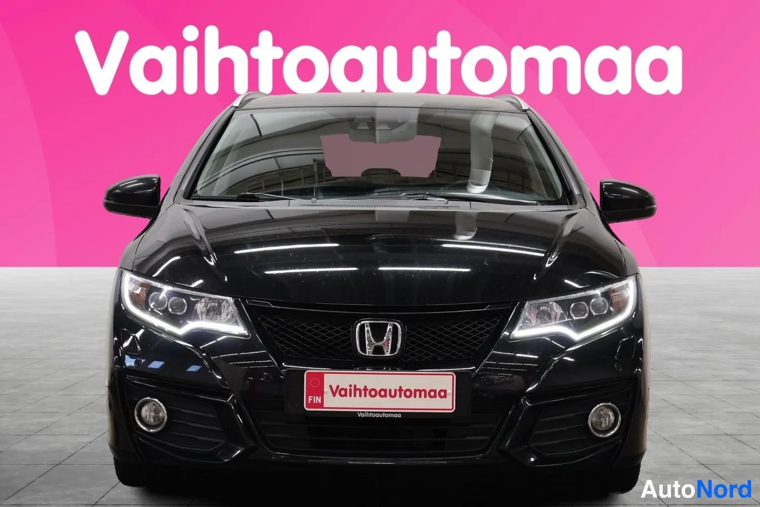 Edestä: Mustan farmariauton etukuva suoraan edestä, säleikkö ja Honda-merkki keskellä, päivätulet päällä.