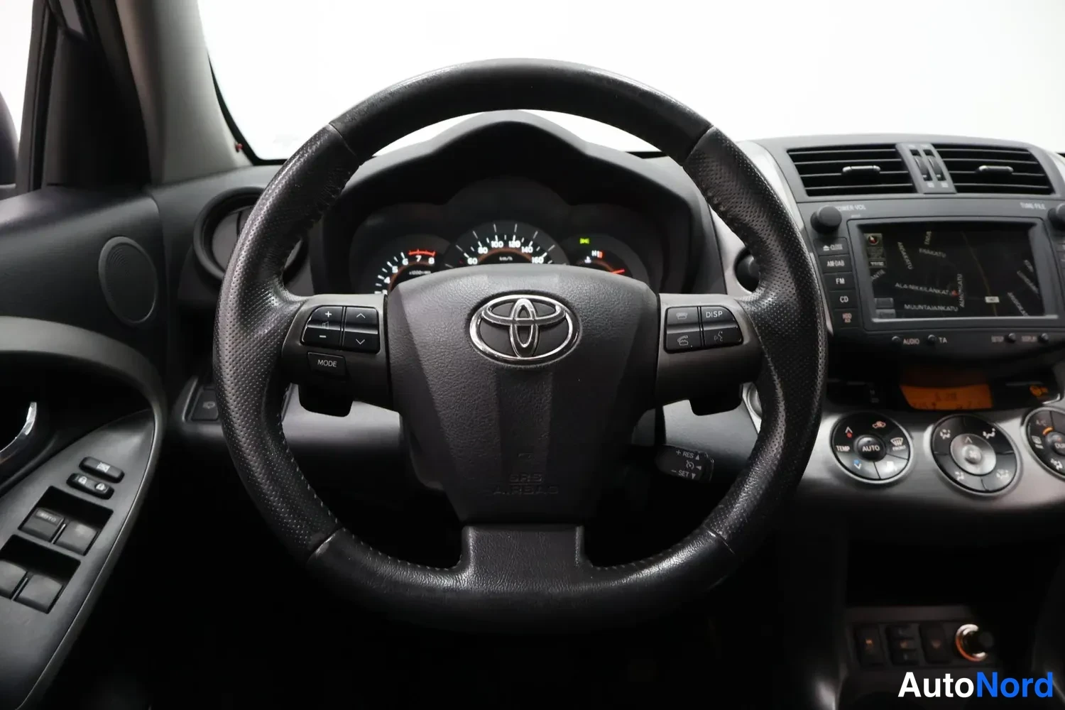 Muu: Etunäkymä ohjauspyörään Toyota-logolla, mittaristo ja kosketusnäytöllinen multimediajärjestelmä, joka näyttää karttaa.