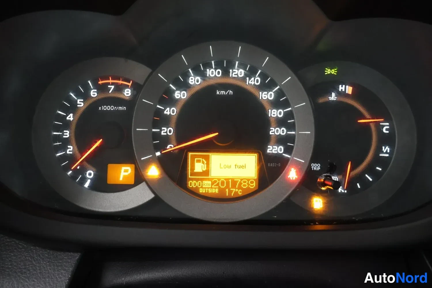Muu: Kojelaudan mittaristo lähikuvassa: nopeusmittari 0–220 km/h, kierroslukumittari, polttoainemittari ja lämpömittari. Näytössä lukee 'Low fuel', 'ODO 201789' ja '