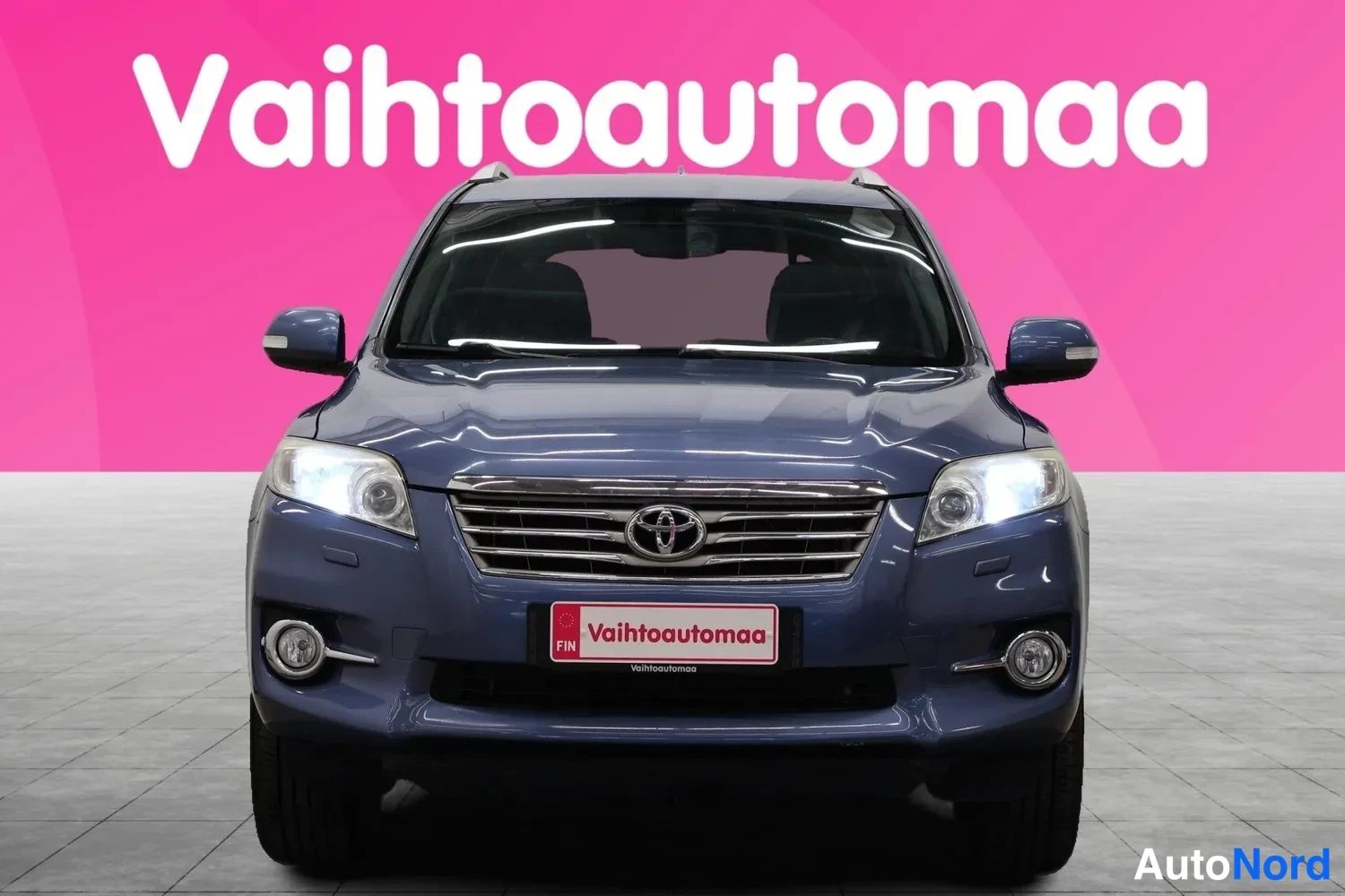 Edestä: Sininen Toyota RAV4 suoraan edestä, etusäleikkö ja ajovalot näkyvissä.