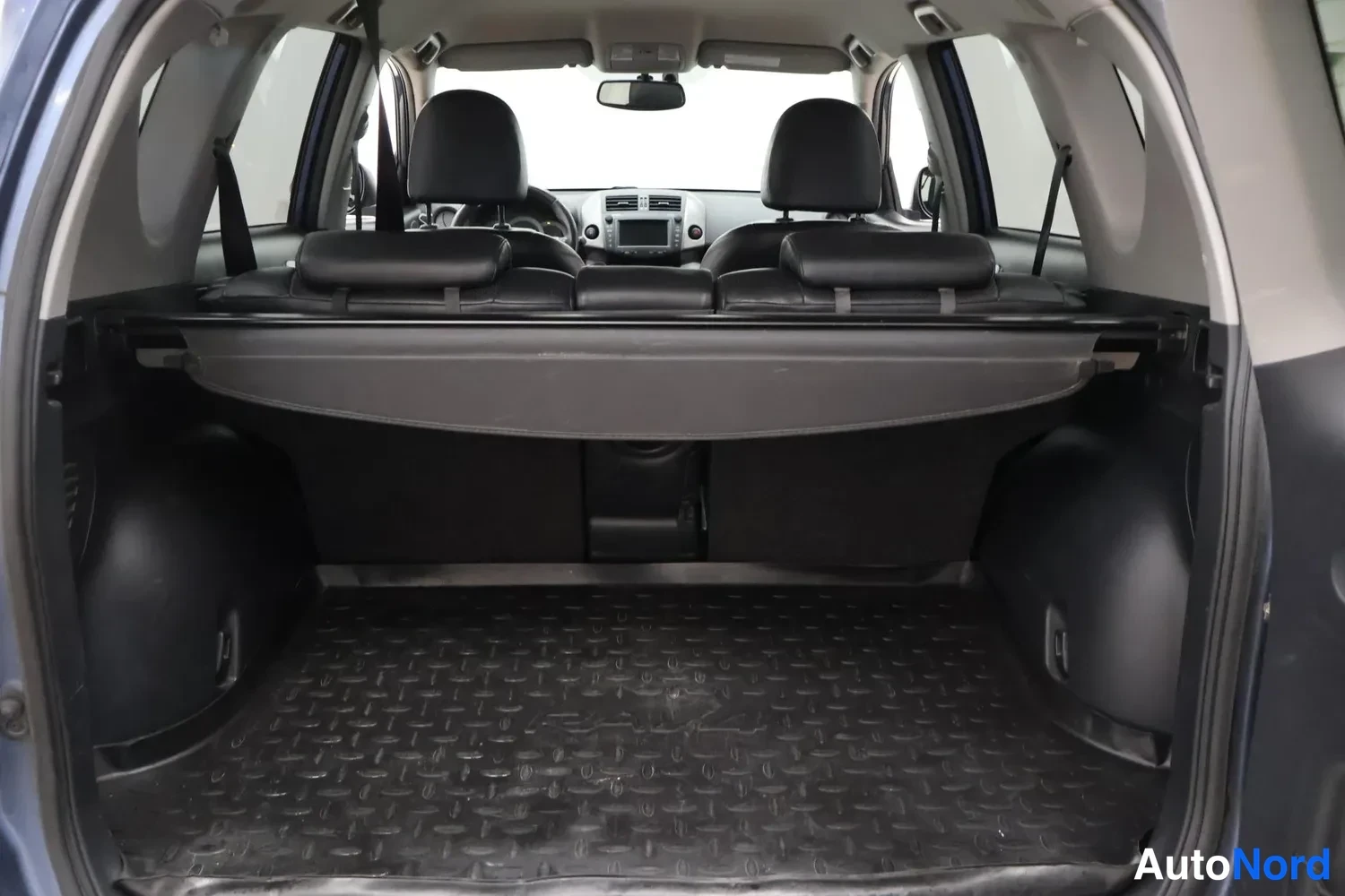 Tavaratila: Cargo view from behind the rear seats looking forward. A cargo cover is raised across the opening of the load area behind the folded-down rear seatbacks and abo