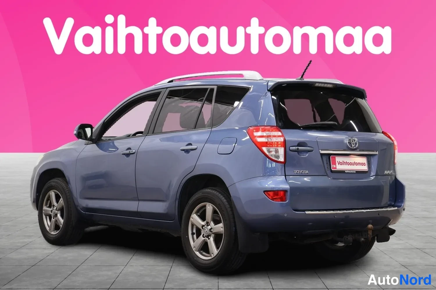 Takaviisto: Sininen Toyota RAV4 takaviistosta oikealta nähtynä, takavalot ja tavaratilan kansi näkyvät.