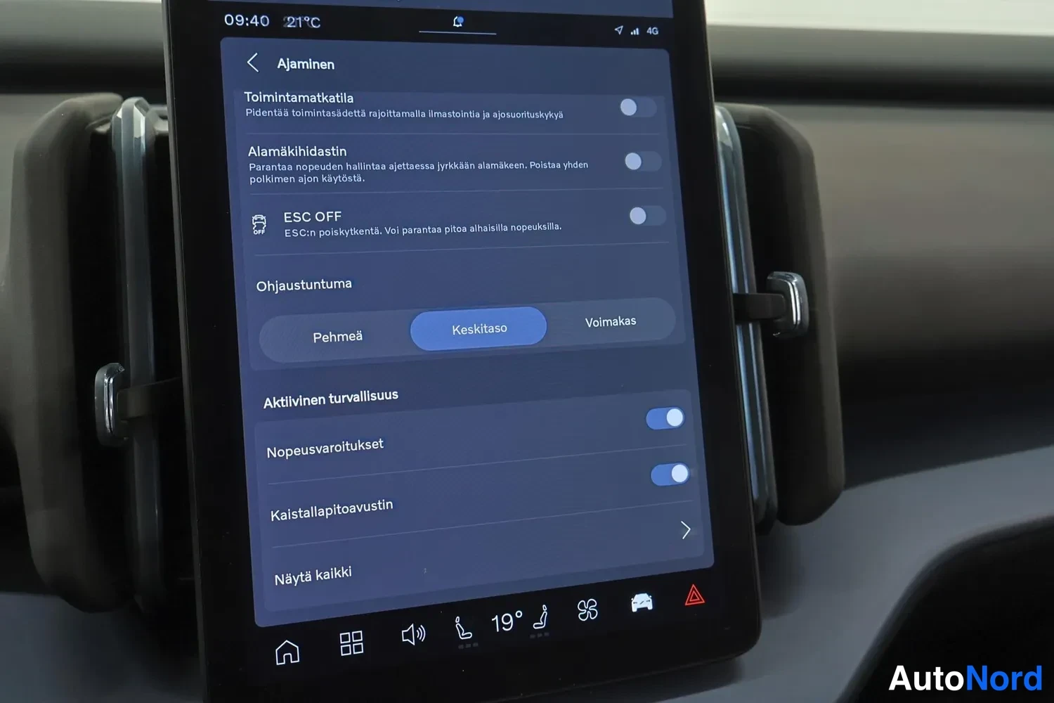 Yksityiskohta: Close-up of the vertical centre screen display showing driving and safety settings menu, with text in Finnish such as ESC OFF, Kaistallapitoavustin, and Ohjaust