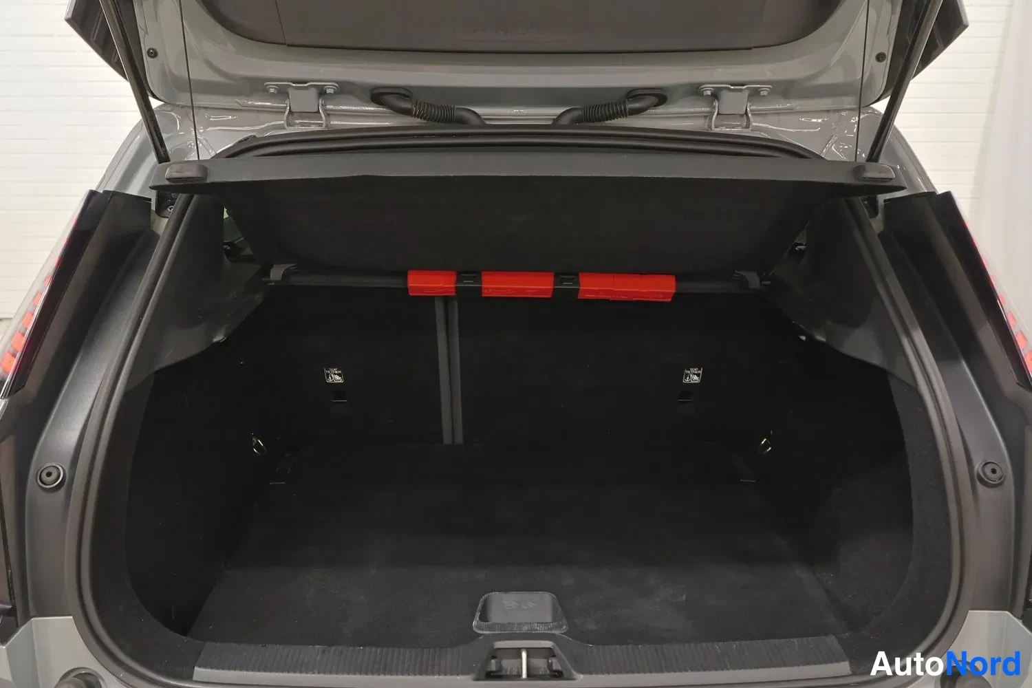 Takaa: Wide angle photograph of the open boot with the luggage compartment shade pulled across, revealing the cargo floor and red storage hooks for the retractable cov