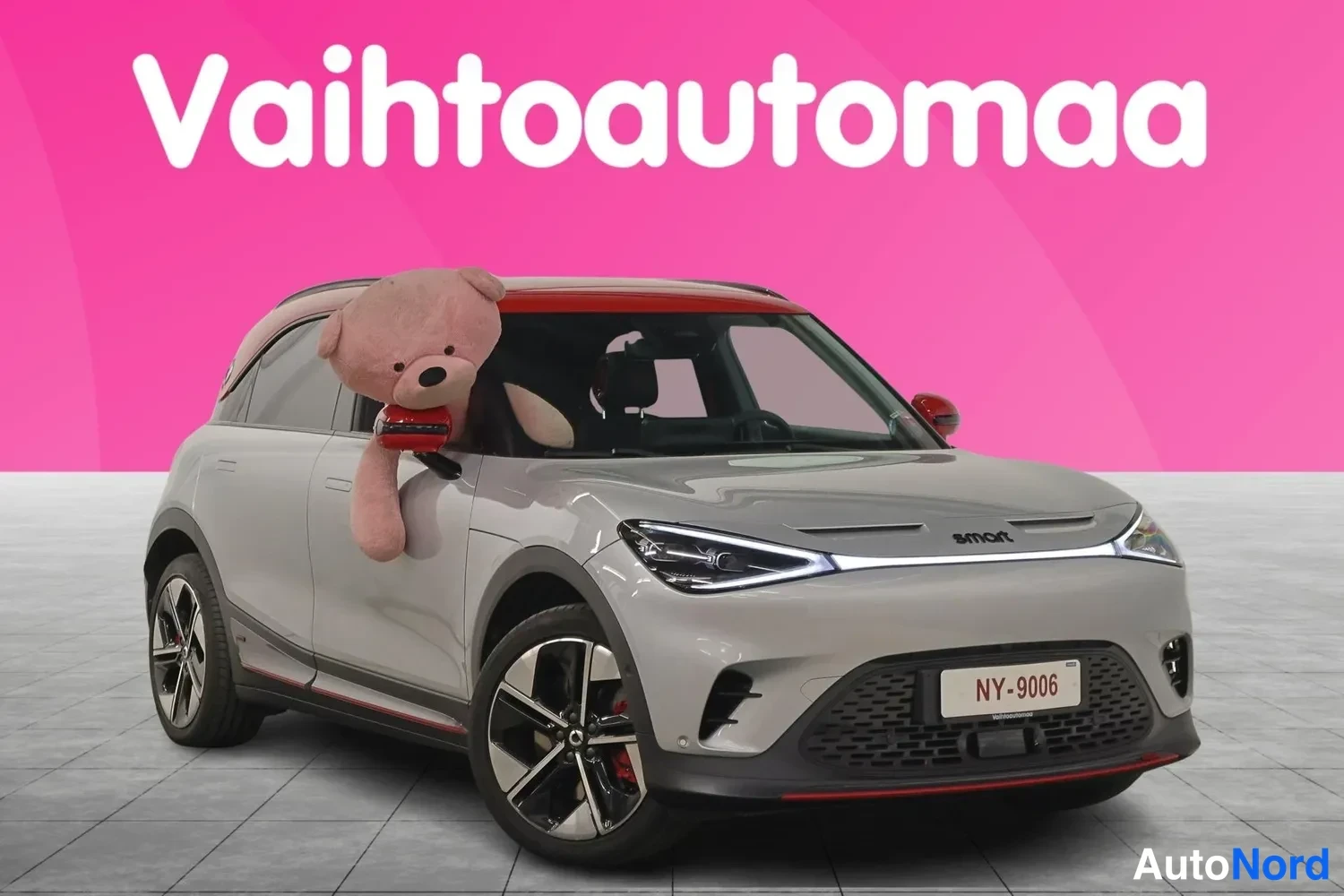 Etuviisto, nokka oikealle: Hopeanharmaa Smart-auto vinosti edestä oikealta, punainen katto ja rekisteri NY-9006.